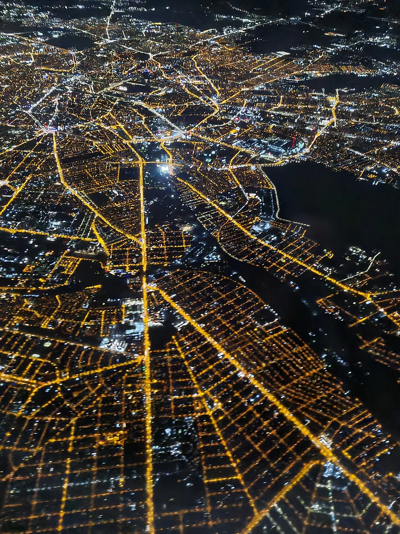 A night-time aerial view over Bucharest, the city's radiating grid of streets brightly lit