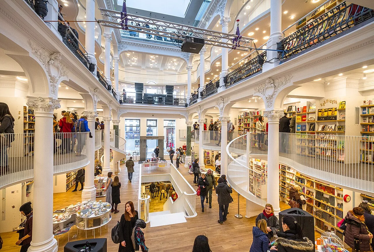 The bright white multi-level atrium of the Cărturești Carusel bookstore in Bucharest, with its spiral staircase and galleried balconies