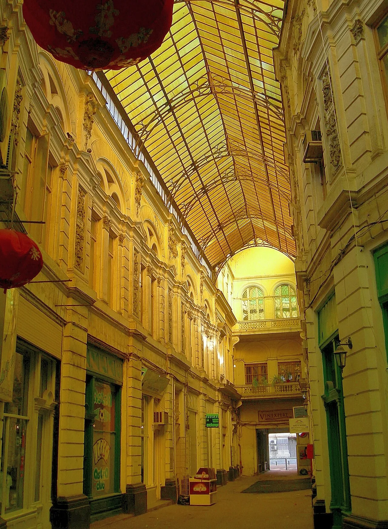 The Macca-Vilăcrosse passage in Bucharest under its distinctive yellow-tinted glass barrel-vault roof, flanked by Belle-Époque facades