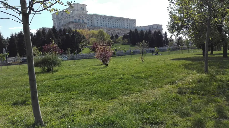 The colossal white classicist Palace of the Parliament (Casa Poporului) seen across a green park in Bucharest
