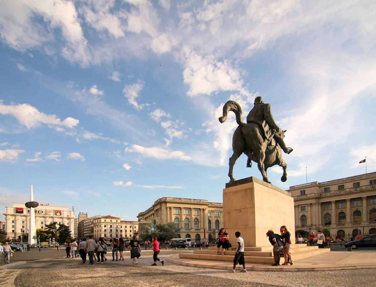 Revolution Square in Bucharest, with the equestrian statue of Carol I before the former Royal Palace and the Memorial of Rebirth spike